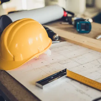 Hardhat sitting on blueprints on a table